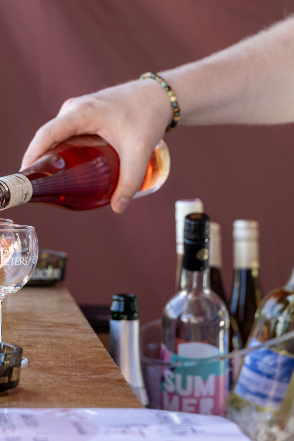 Hand gießt Flüssigkeit in Glas ein.