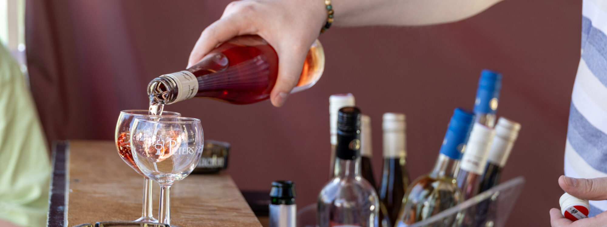Hand gießt Flüssigkeit in Glas ein.