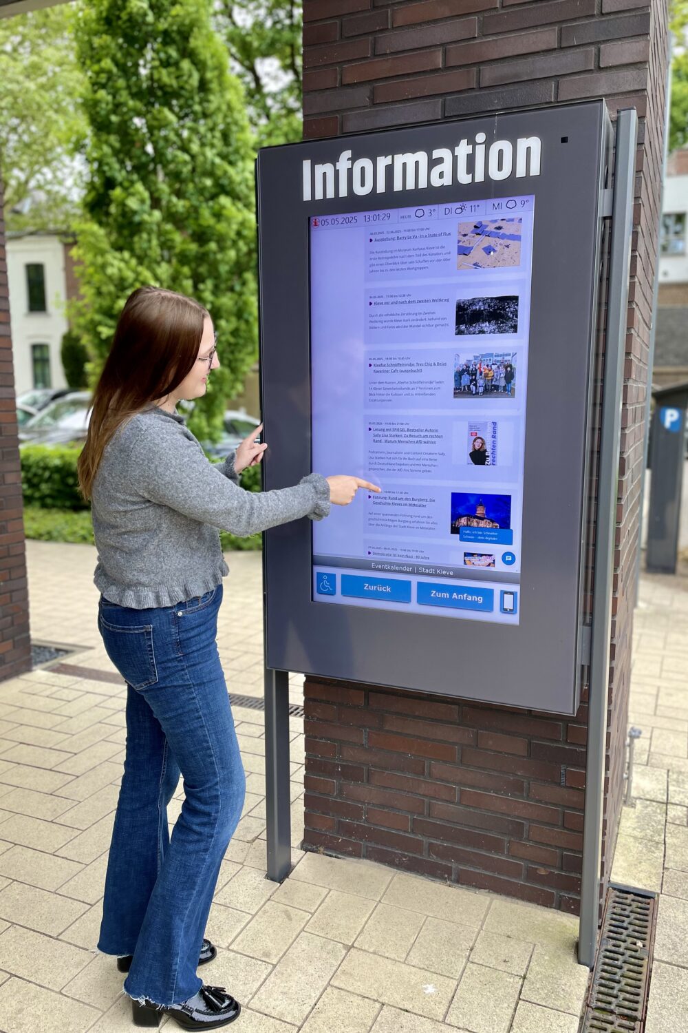 Mitarbeiterin der Tourist Information erklärt die Benutzung des Info-Terminals vor der Tourist Information