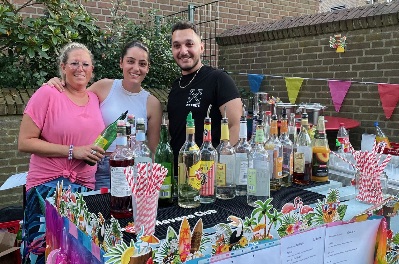 Drei Personen stehen hinter einem Cocktailstand.