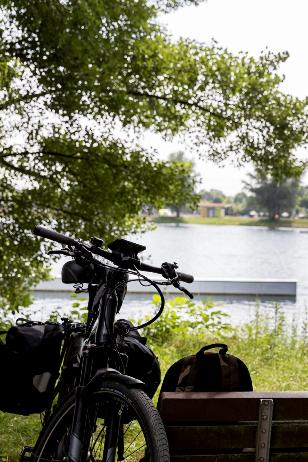Gast mit Fahrrad unterwegs, macht auf einer Bank eine Pause.