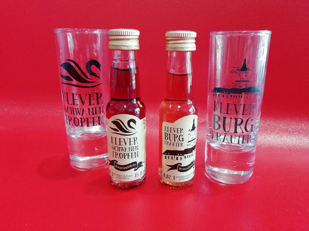 Zwei Liköre und zwei Gläser stehen auf einem roten Untergrund und Hintergrund