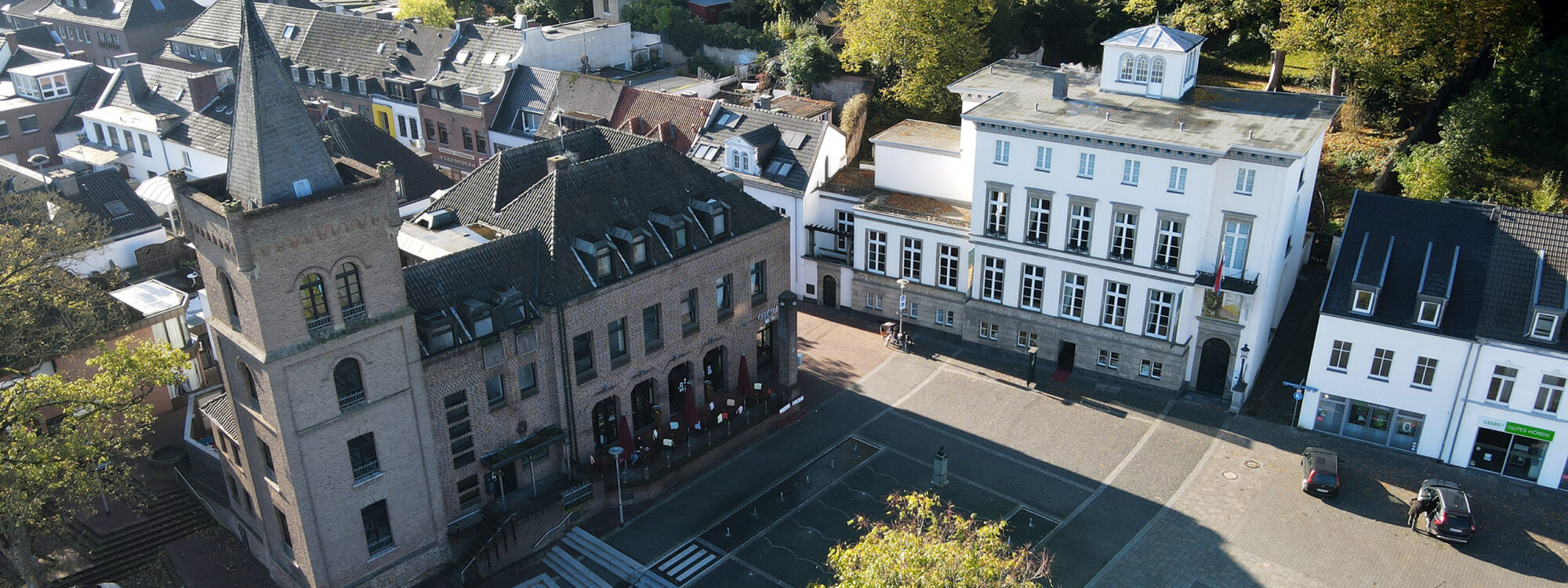 Sicht von oben auf Turm, Marktplatz und ein weißes Gebäude.