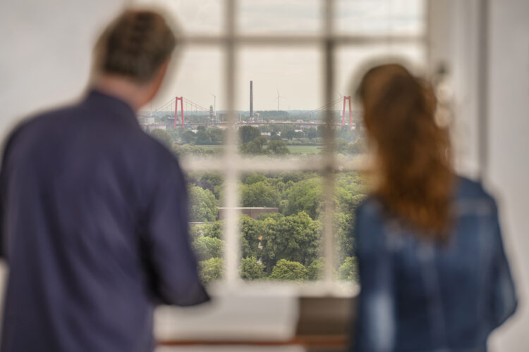 Zwei Personen aus dem Fenster der Schwanenburg. Die Rheinbrücke ist im Hintergrund.
