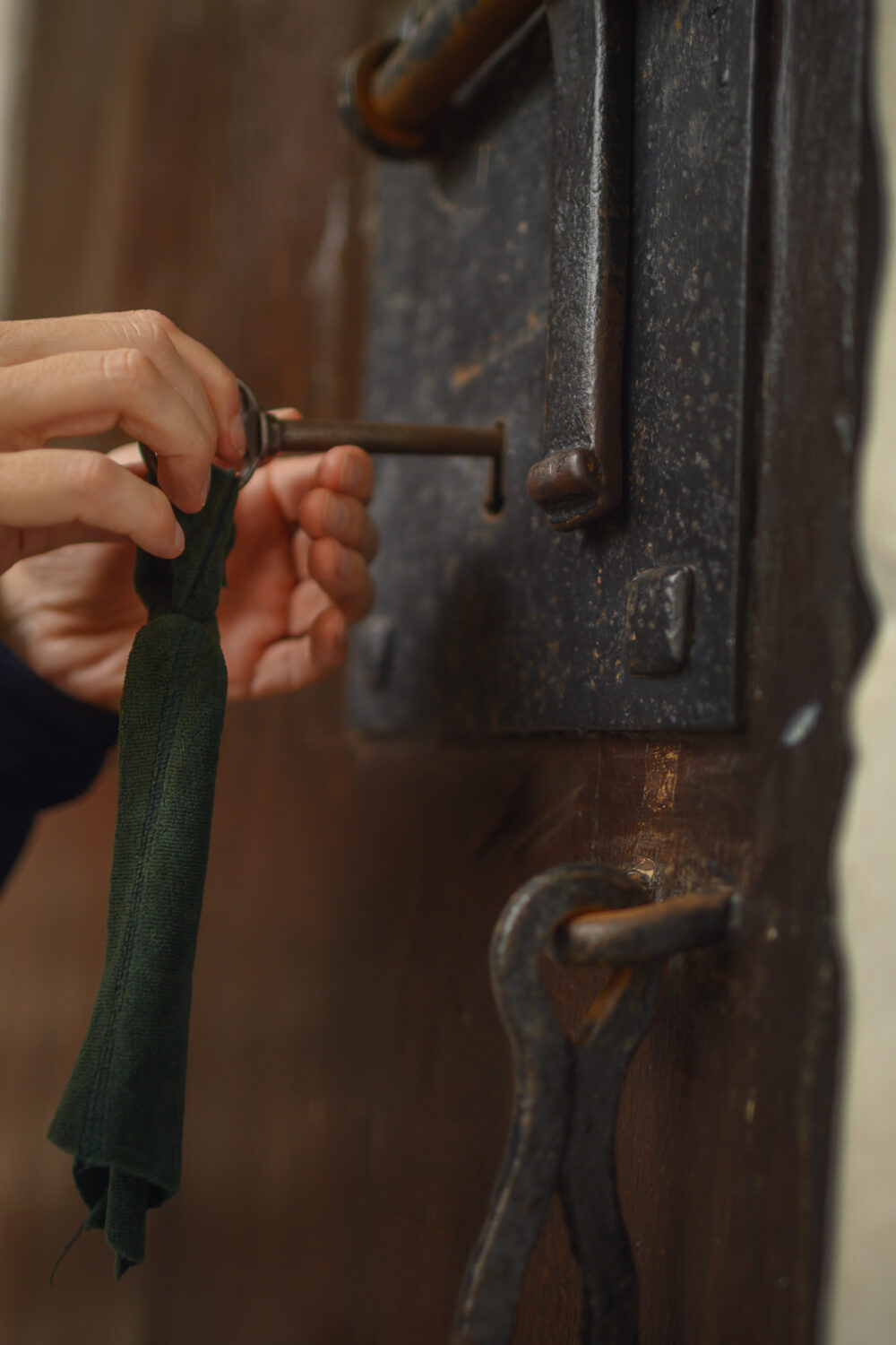 Hände drehen einen alten Schlüssel in einem großen, dunklen Schloss an einer Holztür an der Schwanenburg