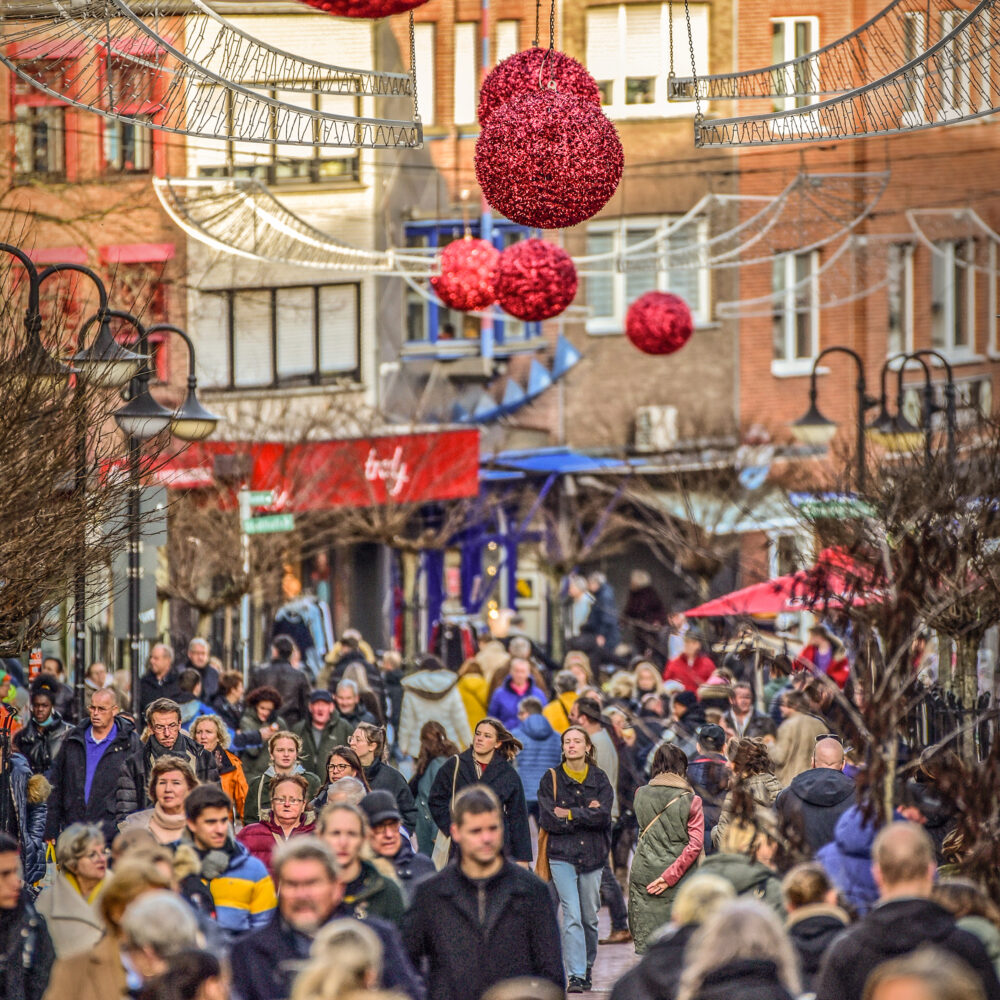 Viele Menschen laufen durch eine Innenstadt.