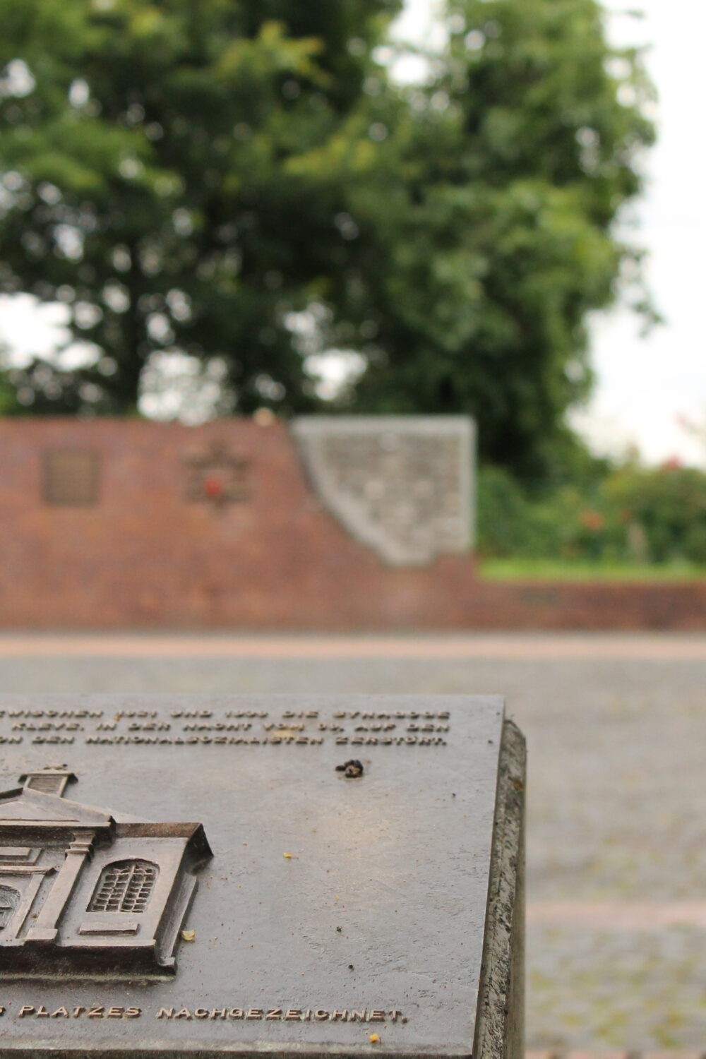 Bronzetafel in Kleve mit Relief einer Synagoge im Vordergrund, im Hintergrund eine Mauer mit einem Davidstern. Text auf der Tafel: 'Hier stand die Synagoge, die 1938 zerstört wurde.'