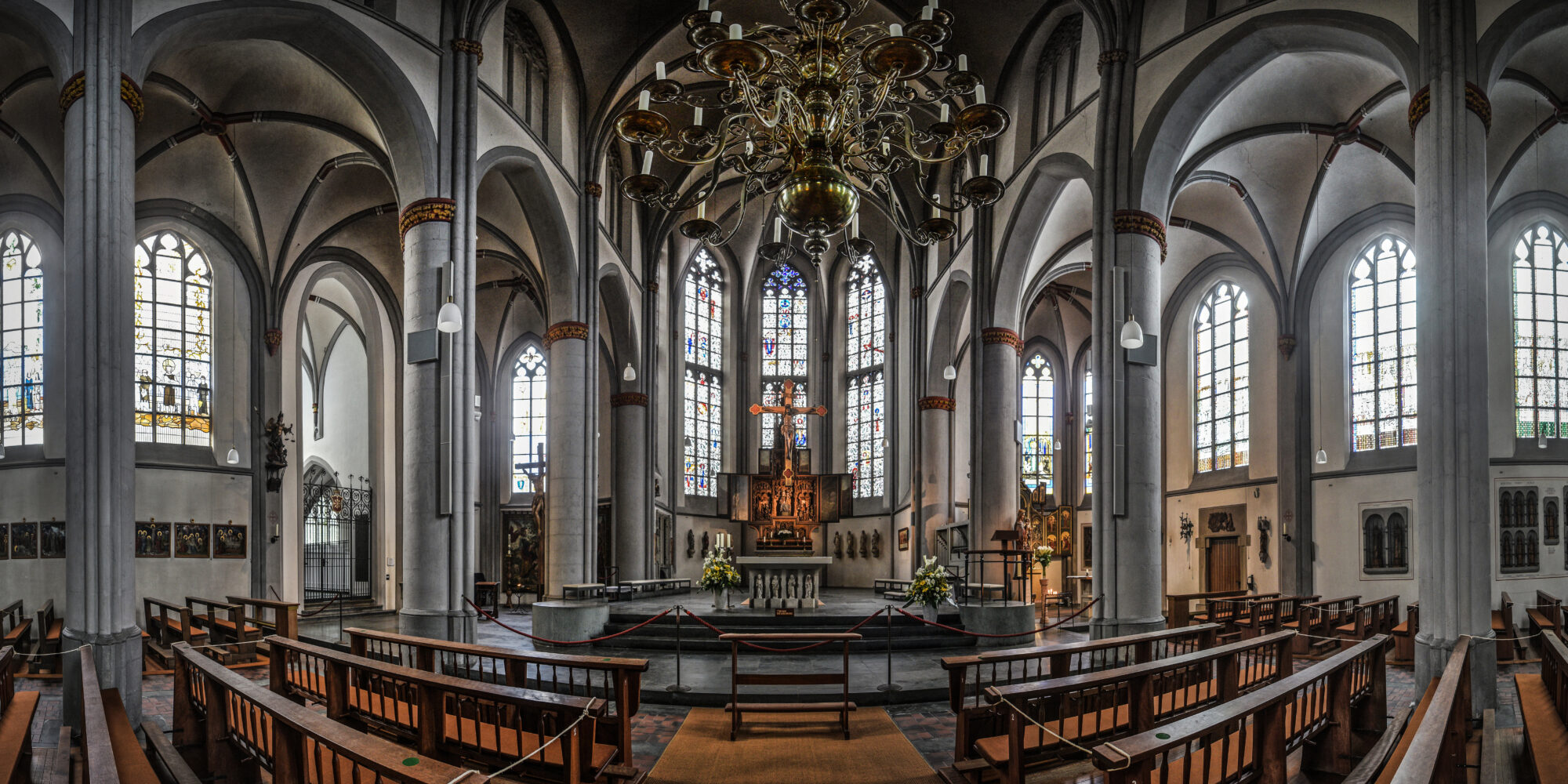 Innenansicht der Stiftskirche mit Pfeilern, Bögen und Altar.