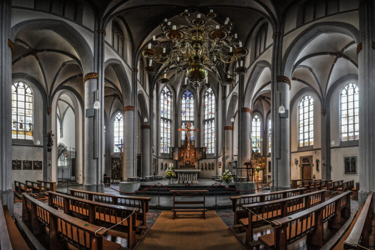 Innenansicht der Stiftskirche mit Pfeilern, Bögen und Altar.