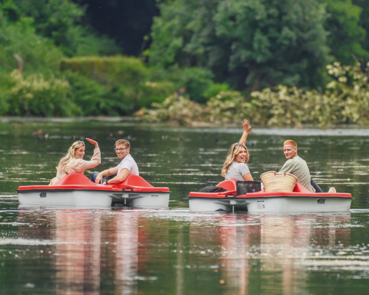 Zwei rote Treetboote, jeweils ein Mann und eine Frau fahren gemeinsam Treetboot auf dem Kermisdahl