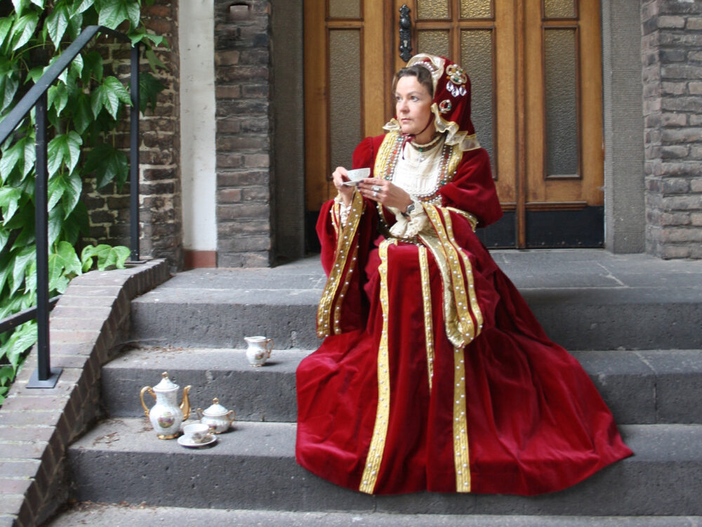 Eine Frau ist in einem rot goldenen Kleid kostümiert und sitzt auf einer Treppe