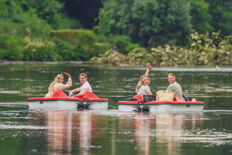 Vier junge Menschen auf Tretbooten im Wasser