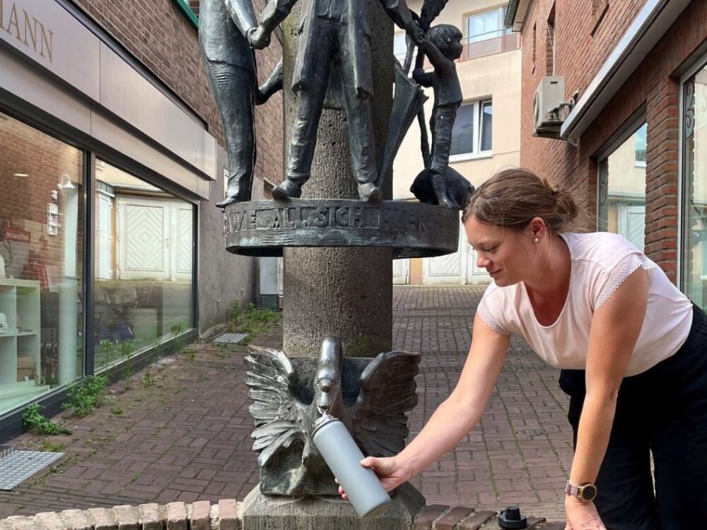 Frau füllt Trinkflasche am Janusbrunnen